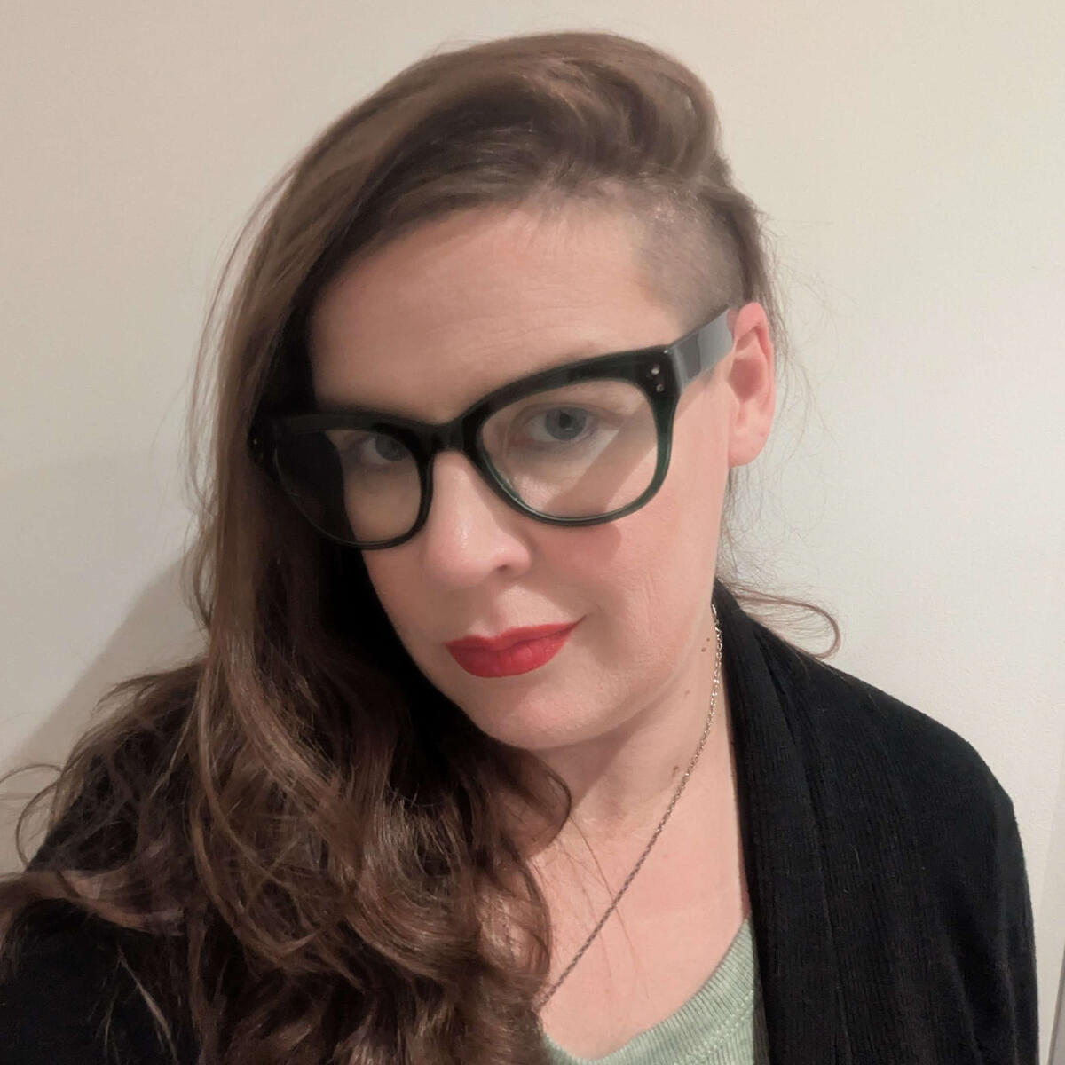 Darcy headshot Darcy, a white non-binary person dressed as Rosie the Riveter and wearing over-ear headphones